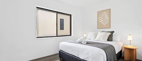 Rest easy in the primary bedroom with a queen bed and a ceiling fan overhead, perfect for a peaceful night after a day in the surf.
