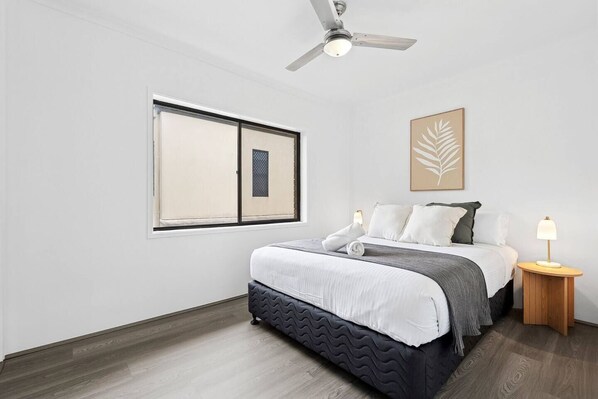 Rest easy in the primary bedroom with a queen bed and a ceiling fan overhead, perfect for a peaceful night after a day in the surf.