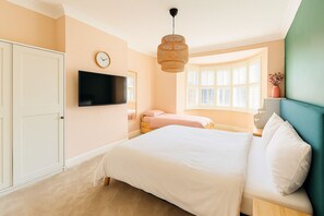 Master bedroom with super king bed, single bed, and en-suite shower room. Spacious and sunlit with calming pastel tones and a bay window for cozy mornings. The perfect blend of luxury and comfort for your stay!