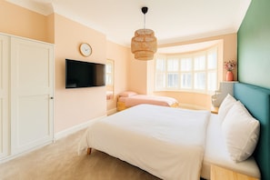 Master bedroom with super king bed, single bed, and en-suite shower room. Spacious and sunlit with calming pastel tones and a bay window for cozy mornings. The perfect blend of luxury and comfort for your stay!