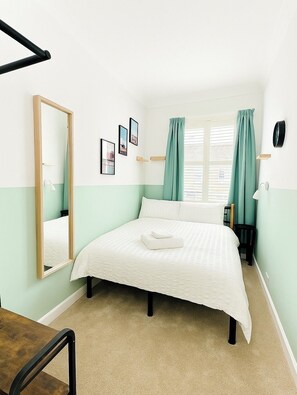 Cozy and bright double bedroom with fresh green accents, plush carpet, and a large window flooding the room with natural light. (1)