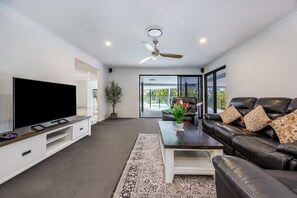 Spacious lounge with pool views, leather sofas, and smart TV
