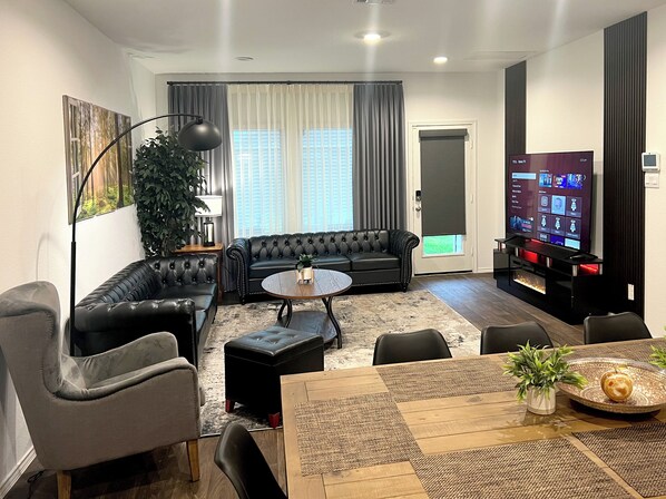 Living room with plenty of seating space and 75" Smart TV and electric fireplace