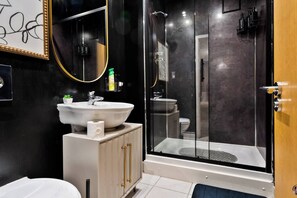 Modern en-suite bathroom with a sleek walk-in shower, complete with shower gel, shampoo, and conditioner.