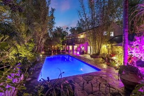 Tropical resort-like backyard with beautiful lighting and a sparkling heated pool.