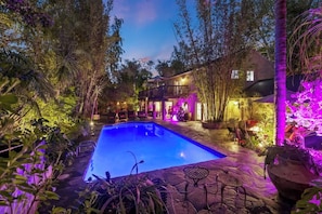 Tropical resort-like backyard with beautiful lighting and a sparkling heated pool.