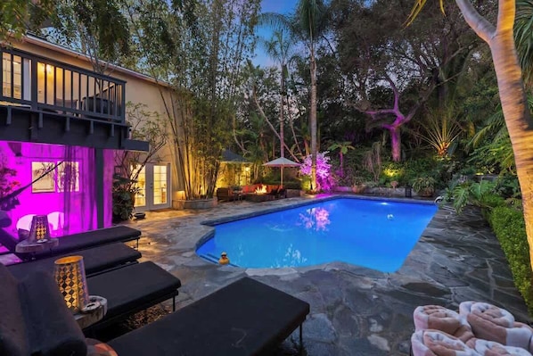 Tropical resort-like backyard with beautiful lighting and a sparkling heated pool.