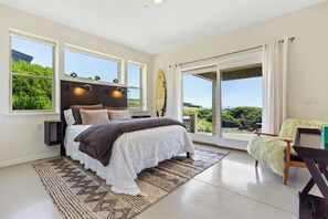 King sized bed, access to the patio, and sweeping views of the Pacific ocean. 