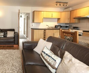 Living area with sofas and view of dining area and kitchen with cooker, microwave, kettle