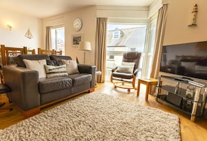 lounge area with double leather sofa, armchair and TV.
