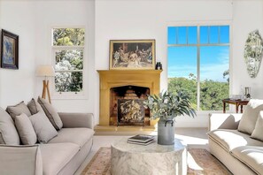 Experience the pure tranquillity of this elegant living room, ideal for entertaining or quiet afternoons on the sofas, complemented by leafy views through expansive windows.