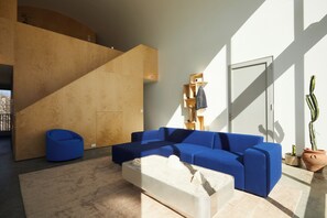 Living room w/couch, art deco coffee table and floor to ceiling windows.