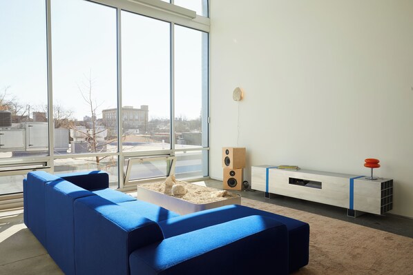 Living room w/couch, art deco coffee table and floor to ceiling windows.
