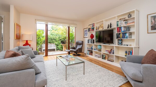 Light and bright open plan living space with smart TV and large doors onto courtyard