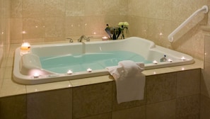 Unwind in a soothing spa tub surrounded by soft candlelight for a truly relaxing experience.