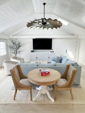 Large, light-filled family room with smart TV and game table.