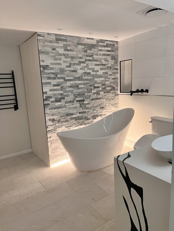 Primary Suite, heated towel rack, wall mount faucets, backlit freestanding tub.