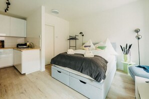 Ein Ort zum Wohlfühlen: Das weiche Bett lädt zum Träumen ein, während die moderne Küche bereitsteht für deinen ersten Kaffee. Sanfte Farben und stilvolle Details schaffen eine Atmosphäre der Ruhe – dein perfekter Rückzugsort inmitten des Stadtlebens.