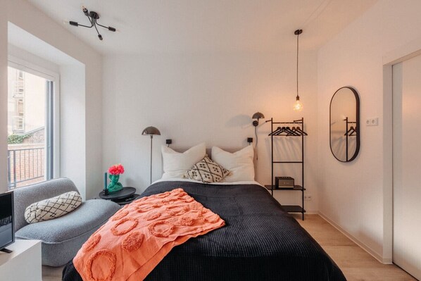 Ein stilvoller Rückzugsort mit modernem Design und gemütlichem Flair. Genieße das weiche Bett, entspanne im Sessel am Fenster oder lausche sanfter Musik. Warme Farbakzente und sanftes Licht schaffen eine Atmosphäre, die Ruhe und Inspiration vereint.