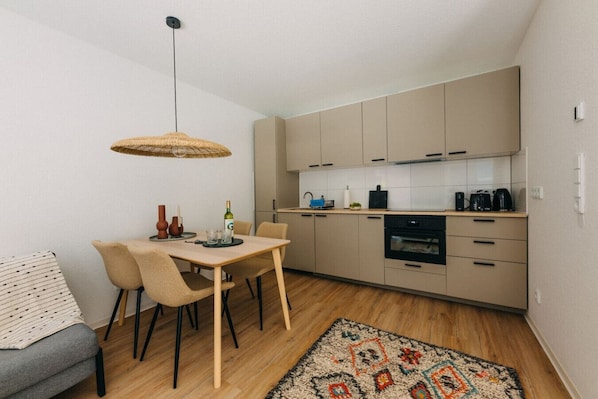 Die offene Wohnküche verbindet Funktionalität mit Stil. Warme Erdtöne, natürliche Materialien und modernes Design schaffen eine gemütliche Atmosphäre. Perfekt ausgestattet für gemeinsame Mahlzeiten oder entspannte Abende mit einem Glas Wein.