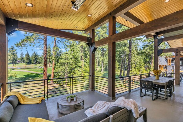 Expansive covered deck with lounge and dining, nestled in pine.