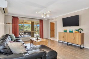 Lounge in the main living area, where a leather L-shaped sofa, timber details, and thoughtful artwork create a warm, inviting space to unwind with your favourite shows.