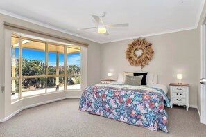 Retreat to the calming primary bedroom, featuring a queen-sized bed adorned with vibrant floral bedding and a charming bay window with hill views.