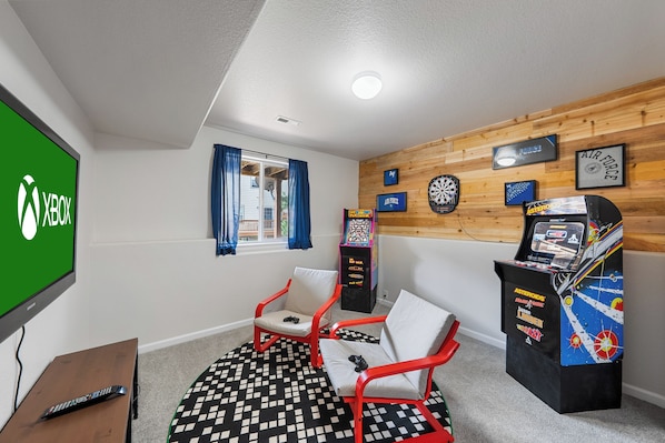 The arcade room features arcade consoles, Xbox, SuperNintendo, dart board, games