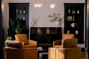 Step into our cozy music room - where comfortable caramel-colored seating, a vintage piano, and stunning decor combine to create the perfect atmosphere for relaxing and unwinding with friends and family!