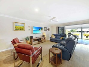 Relax in the spacious, light-filled living room featuring comfortable seating, a smart TV, and seamless indoor-outdoor flow to the waterfront terrace.