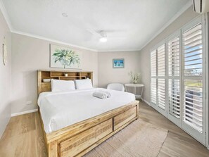 The primary bedroom is drenched in natural light with a ceiling fan and comfortable queen bed.
