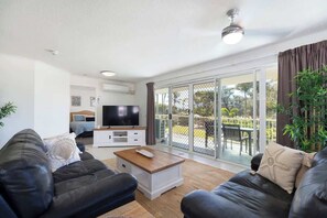 Relax in the bright and breezy open-plan lounge, complete with air-conditioning, a ceiling fan, and direct access to the wrap-around deck—perfect for unwinding after a day in the sun.