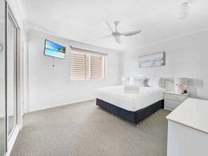Rest easy in the main bedroom with a queen bed, ceiling fan, TV, and built-in wardrobe.