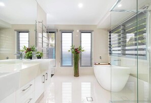 Unwind in the private ensuite off the primary bedroom, featuring a relaxing bathtub, spacious vanity, and fresh, hotel-quality towels.