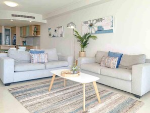 Relax in the open-plan living area, where floor-to-ceiling windows frame peaceful marina views and the coastal breeze flows in.