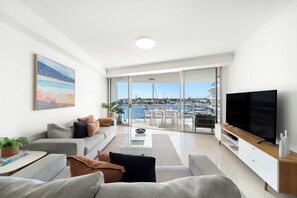 Relax in the open-plan living area, where floor-to-ceiling windows frame peaceful marina views and the coastal breeze flows in.