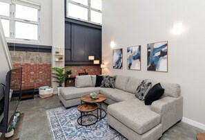 Living area w/ large windows, cozy sectional, 55" smart TV & desk workspace