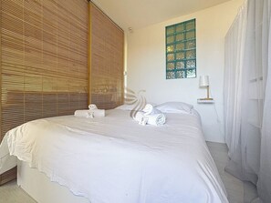 La cloison en bois ajoute une atmosphère chaleureuse et intime, parfaite pour se reposer dans cette chambre apaisante. Les briques de verre offrent un éclairage diffus agréable tout au long de la journée.