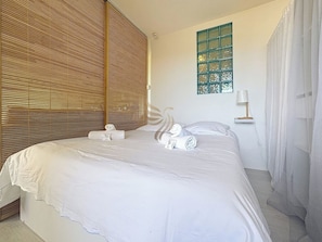 La cloison en bois ajoute une atmosphère chaleureuse et intime, parfaite pour se reposer dans cette chambre apaisante. Les briques de verre offrent un éclairage diffus agréable tout au long de la journée.