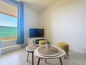Ce salon minimaliste et lumineux permet une belle ambiance relaxante. Profitez de la lumière naturelle pour lire un bon livre ou détendez-vous en regardant la télé. L'espace extérieur promet des déjeuner ensoleillés.