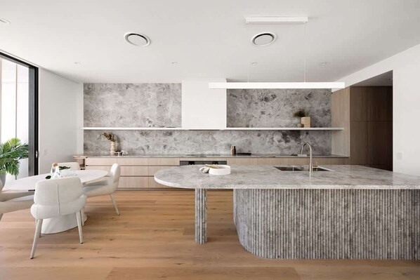 Cook and connect in a sleek kitchen with stone textures and top appliances.