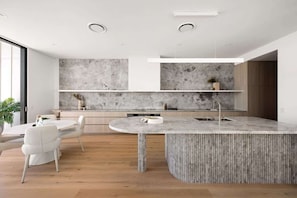 Cook and connect in a sleek kitchen with stone textures and top appliances.