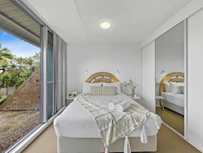 The first bedroom offers a queen bed with sliding doors that extend the shared backyard.