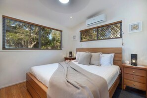 Rest and recharge in the serene primary bedroom featuring a plush king bed, private ensuite, air-conditioning, and ceiling fan for a peaceful night’s sleep.