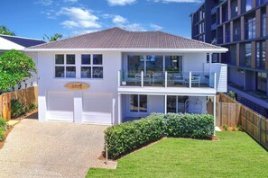 Welcome to your coastal getaway—this bright beach house features a sun-drenched balcony, lush lawn, and relaxed surfside charm just moments from the ocean.