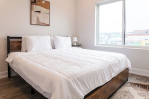 Snuggle up in this inviting bedroom boasting plush beds, a big window framing city views. The thoughtful decor creates a warm and inviting ambiance. #PeacefulSlumber
