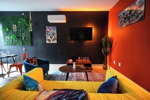 Relax in a cozy living area featuring a comfy sofa, smart TV, and stylish decor—perfect for unwinding or catching up with friends.