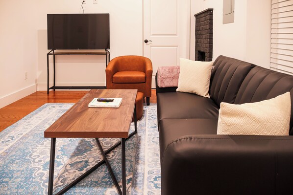 Welcome to our cozy and stylish living room retreat! The space is bathed in natural light, thanks to large windows that offer a picturesque view of the surrounding area. The modern and inviting decor creates a warm atmosphere, perfect for relaxation.