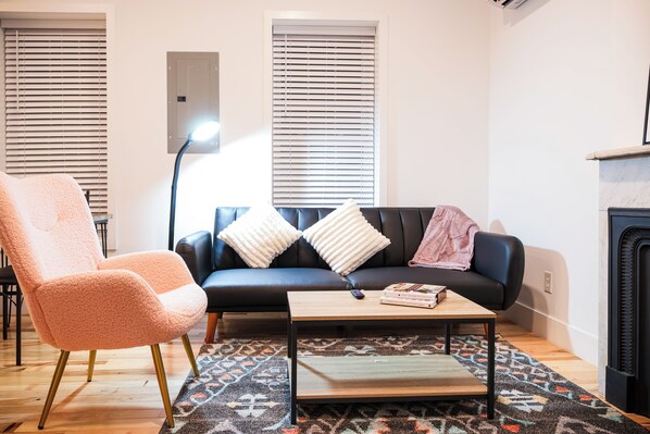 Step into our inviting living room, where plush sofas beckon with promises of comfort and conversations. Bathed in the warm glow of carefully curated lighting, the space seamlessly blends modern elegance with cozy charm. A harmonious fusion of tasteful decor, from vibrant accent pillows to thoughtfully placed art, transforms this room into a haven where relaxation meets refined style.
