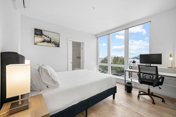 Enjoy a good night's sleep in this sunlit bedroom featuring large windows and a comfortable queen-size bed.